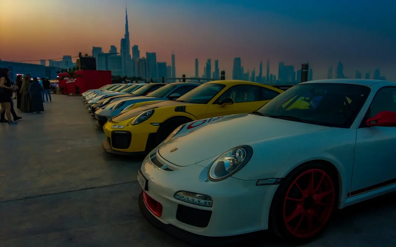 Cars parked in front of the Dubai skyline at dusk